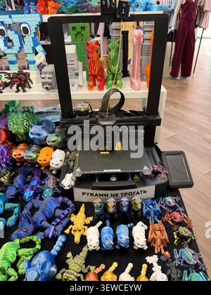 Khimki, Russia - June 25, 2026: 3D printer on display with colorful plastic figurines and toys in a retail setting, various designs visible Stock Photo