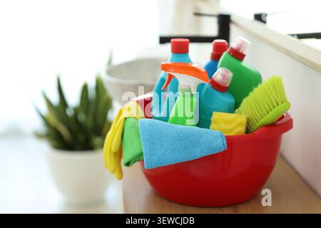 Red plastic basin with cleaning products and supplies on counter in bathroom Stock Photo