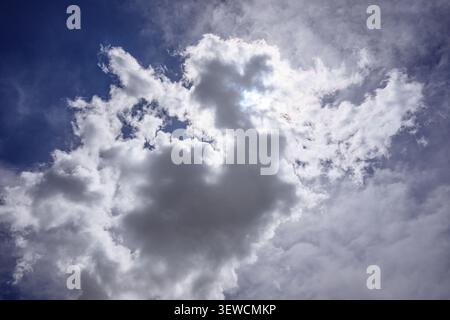 Dramatic sky with fluffy white clouds against deep blue background Stock Photo