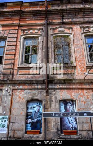 Old brick building with moss-covered windows. Two posters hang in lower windows. Building shows signs of decay and abandonment. Windows have broken pa Stock Photo