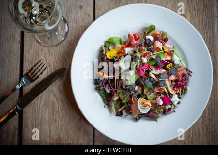Vibrant Salad Creation Adorned With Colorful Flowers and Fresh Greens on Wooden Table Stock Photo