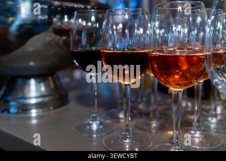 Rows of elegant red wine glasses filled with ruby wine at a tasting. Sophisticated hospitality, fine dining, and winery culture backdrop. Stock Photo