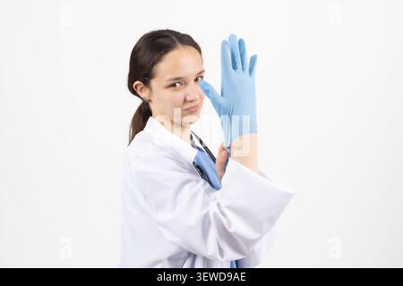 Professional female doctor looking away with medical gloves on blue background Stock Photo
