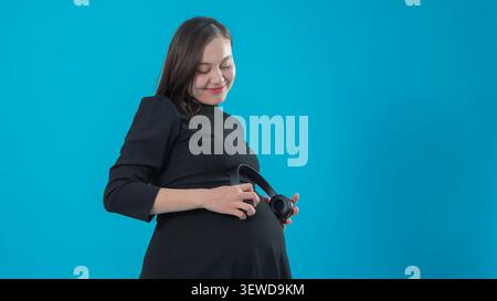 Happy pregnant woman embracing stomach anticipating baby birth in studio Stock Photo