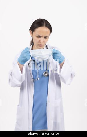 Woman medical worker adjusting facial protection mask before procedure in studio Stock Photo