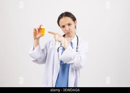 Young woman medical professional presenting vitamins bottle in white studio Stock Photo