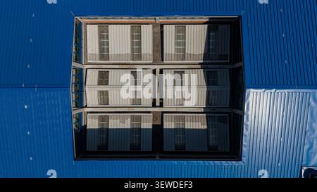 Aerial view of a blue industrial roof featuring rectangular skylights and metal panels in Turin, Piedmont, Italy. Stock Photo