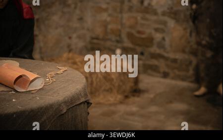 Medieval Scribe Writing with Quill Pen and Ancient Scroll on Wooden Table Stock Photo