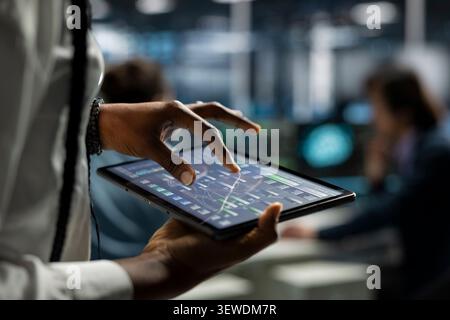 Computer scientist uses a digital tablet in a data center to deploy software updates, configure hardware, and support reliable operations. Stock Photo
