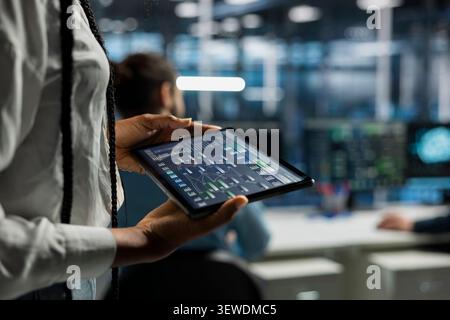 Data center programmer uses a digital tablet in a data center to manage AI systems and optimize server infrastructure. Stock Photo
