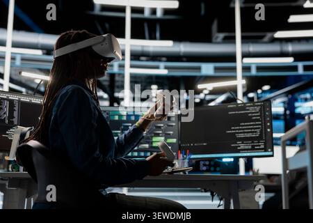 Computer scientist uses a VR headset in a data center to manage AI systems, train neural networks, and configure hardware. Stock Photo