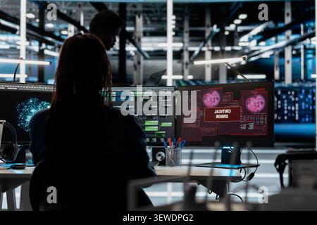 Concerned IT employee reviews warning messages in a data center while troubleshooting errors affecting equipment performance. Stock Photo