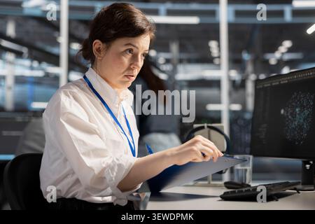 System operator reviews performance analytics on a desktop computer in a data center to optimize storage systems and resource use. Stock Photo