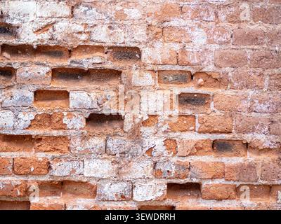 Damaged brick wall texture with crumbling white mortar creating an aged pattern Stock Photo