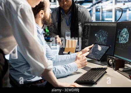 Data center programmers use a digital device in a data center to manage AI simulation and optimize server infrastructure. Stock Photo