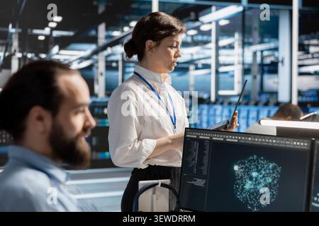 Data center team uses a desktop computer in a data center to manage AI virtualization and optimize server infrastructure. Stock Photo