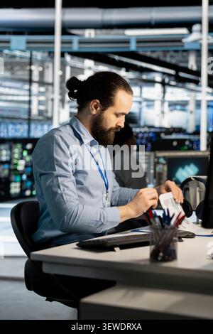 Data center specialist reviews technical paperwork and performance charts to pinpoint server equipment issues. Stock Photo