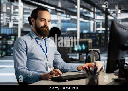 Data center worker works on a computer to monitor AI systems, neural networks and server infrastructure. Stock Photo
