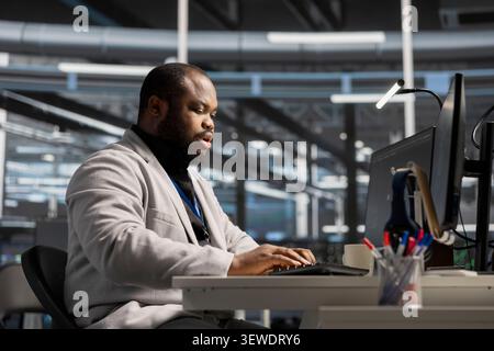 System administrator uses a computer to run diagnostics, update servers and check infrastructure performance. Stock Photo