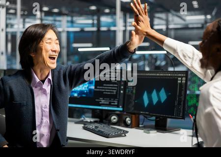 Engineers celebrate in a server hub after successfully programming with generative AI assistance. Stock Photo