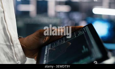 Server facility software developer working with tablet to review code for automation scripts. Stock Photo