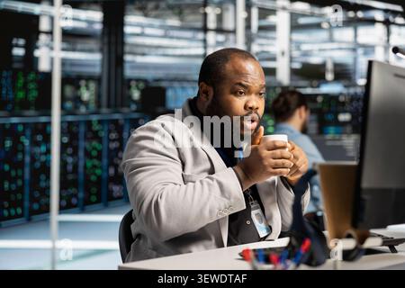 Data center technician uses a computer to run diagnostics, update servers and check infrastructure performance. Stock Photo