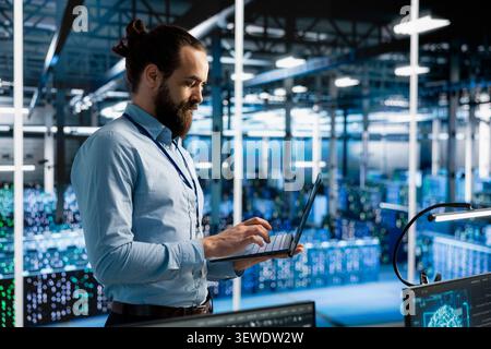 Data center programmer manages databases supporting AI applications and data mining in a server facility. Stock Photo