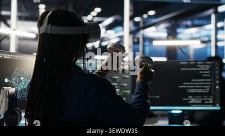 Data center technician uses a VR headset to analyze datasets and manage AI database workflows in a server room. Stock Photo