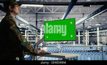 Military IT specialist reviews reconnaissance information on a green screen computer inside a server room. Stock Photo