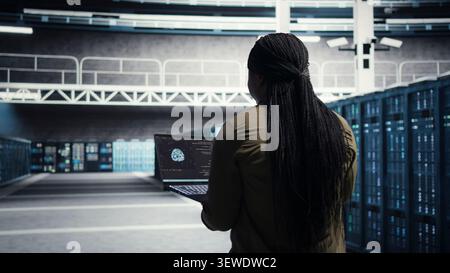 Data center engineer uses laptop in a data center to upgrade server hardware and improve workload capacity. Stock Photo