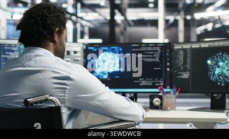 Worker using a wheelchair operates AI node tree software in a data center to monitor performance data. Stock Photo