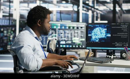 Worker using a wheelchair operates AI node tree software in a data center to monitor performance data. Stock Photo