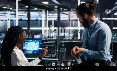 Data center engineering team uses deep learning tools on a digital device in a server room to improve AI operations and system efficiency. Stock Photo