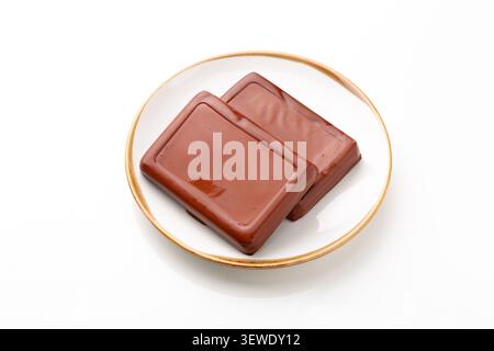 Two blocks of traditional Chinese spiced firm tofu on a ceramic plate, isolated on a white background. Stock Photo