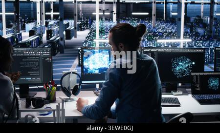 Engineering team checks infrastructure diagnostics on a computer workstation in a server room for IT maintenance. Stock Photo