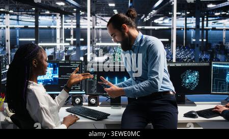 Woman programs on a computer workstation in a data center with generative AI assistance. Stock Photo
