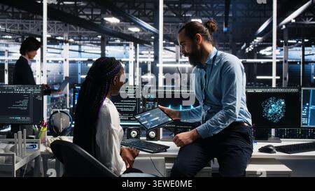 System administrator and employee programs on a computer workstation in a server hub with generative AI assistance. Stock Photo