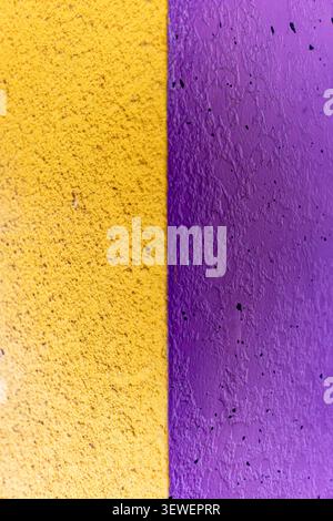 A vibrant and textured wall featuring vertical sections of yellow and purple paint, creating a striking contrast. Perfect for backgrounds, artistic pr Stock Photo