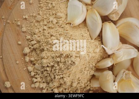 Ground ginger and garlic on wooden board with fresh cloves Stock Photo