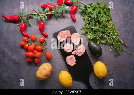Raw Beef Bone Marrow Slices on Black Cutting Board With Vegetables and Herbs Stock Photo