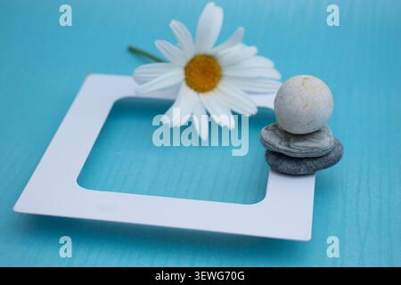 Balanced zen stones with white daisy on blue background Stock Photo