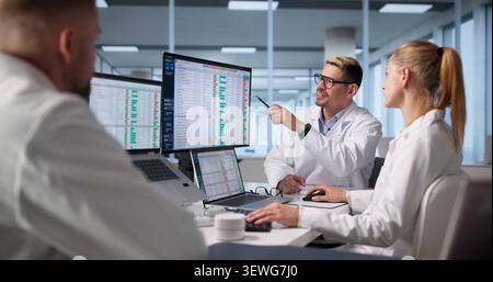 Medical Billing Team Works Together Reviewing Patient Codes On Computers. Stock Photo