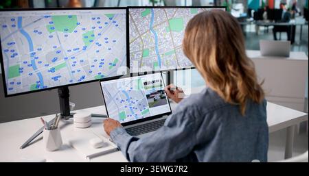 Woman Using Laptop In Office Checking City Land Maps For Valuation Project Stock Photo