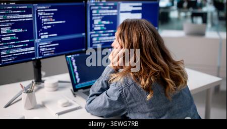 Frustrated Woman Developer Looks Tired While Fixing Coding Mistakes At Office. Stock Photo