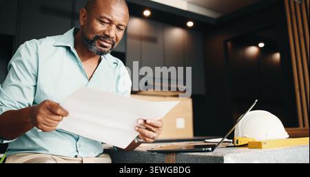 Black man, new home and blueprint for renovation, layout design or real estate maintenance. Mature person, document or laptop for architectural Stock Photo