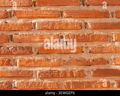 Rough red and orange terracotta bricks forming a textured wall background Stock Photo