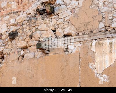 Weathered texture of an ancient wall with visible stone, mud, and timber elements Stock Photo
