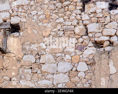 Rough texture of ancient stone wall with visible mortar and deterioration, creating a historic background Stock Photo