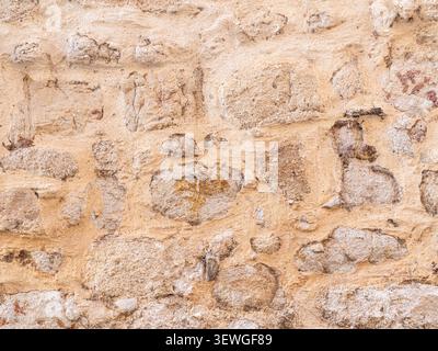 Rustic stone wall featuring textured surface with visible erosion and rough construction Stock Photo