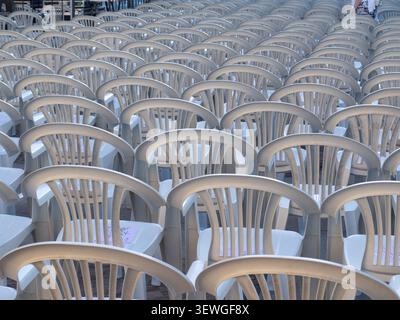 White plastic chairs arranged in neat rows fill an outdoor event venue Stock Photo